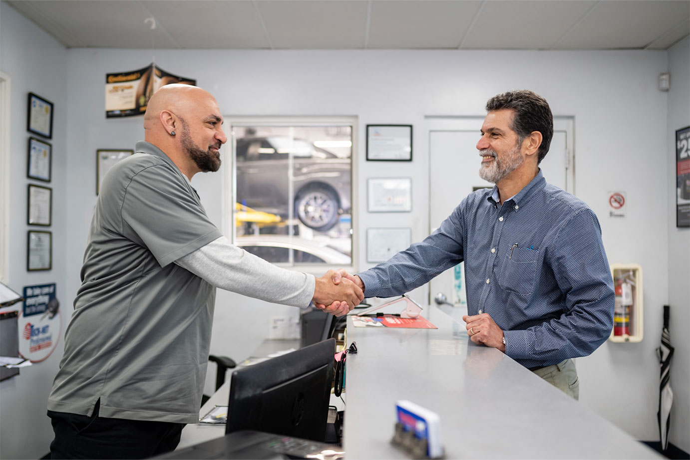 Image of two men shaking hands across a counter in an automotive service center.