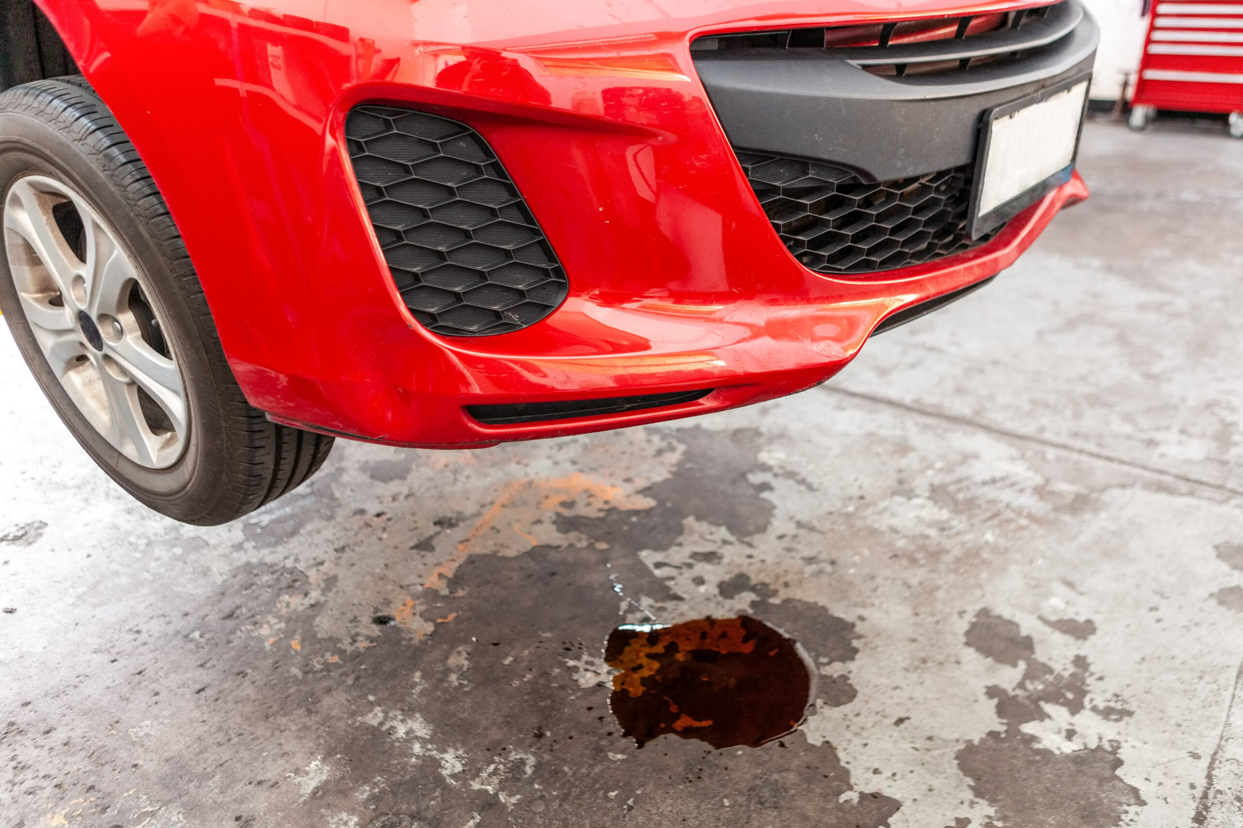 car oil leak depicted with red vehicle and puddle of oil underneath