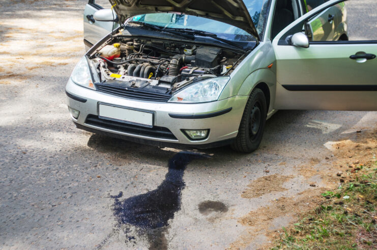 Broken-down car with hood up and liquid leaking from underneath