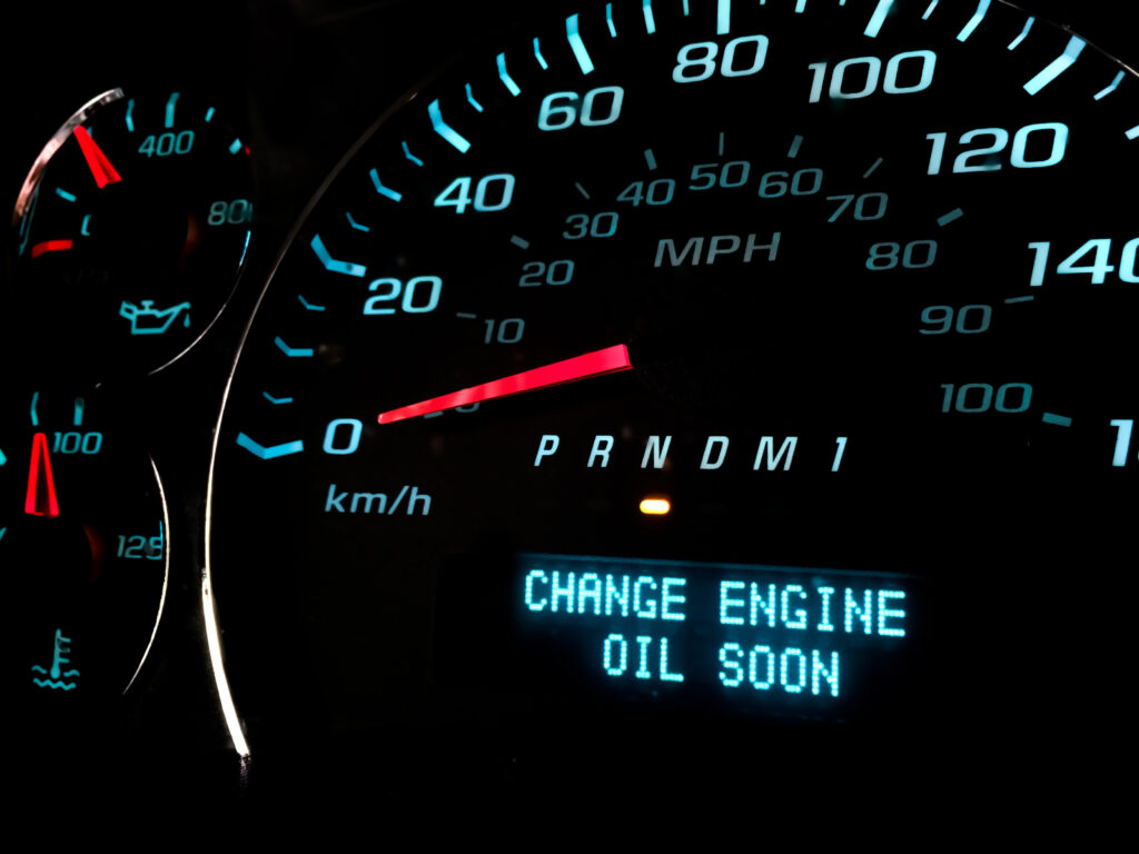 A close-up of a car's dashboard showing the speedometer, gear indicator, and an illuminated warning message that reads, "CHANGE ENGINE OIL SOON."